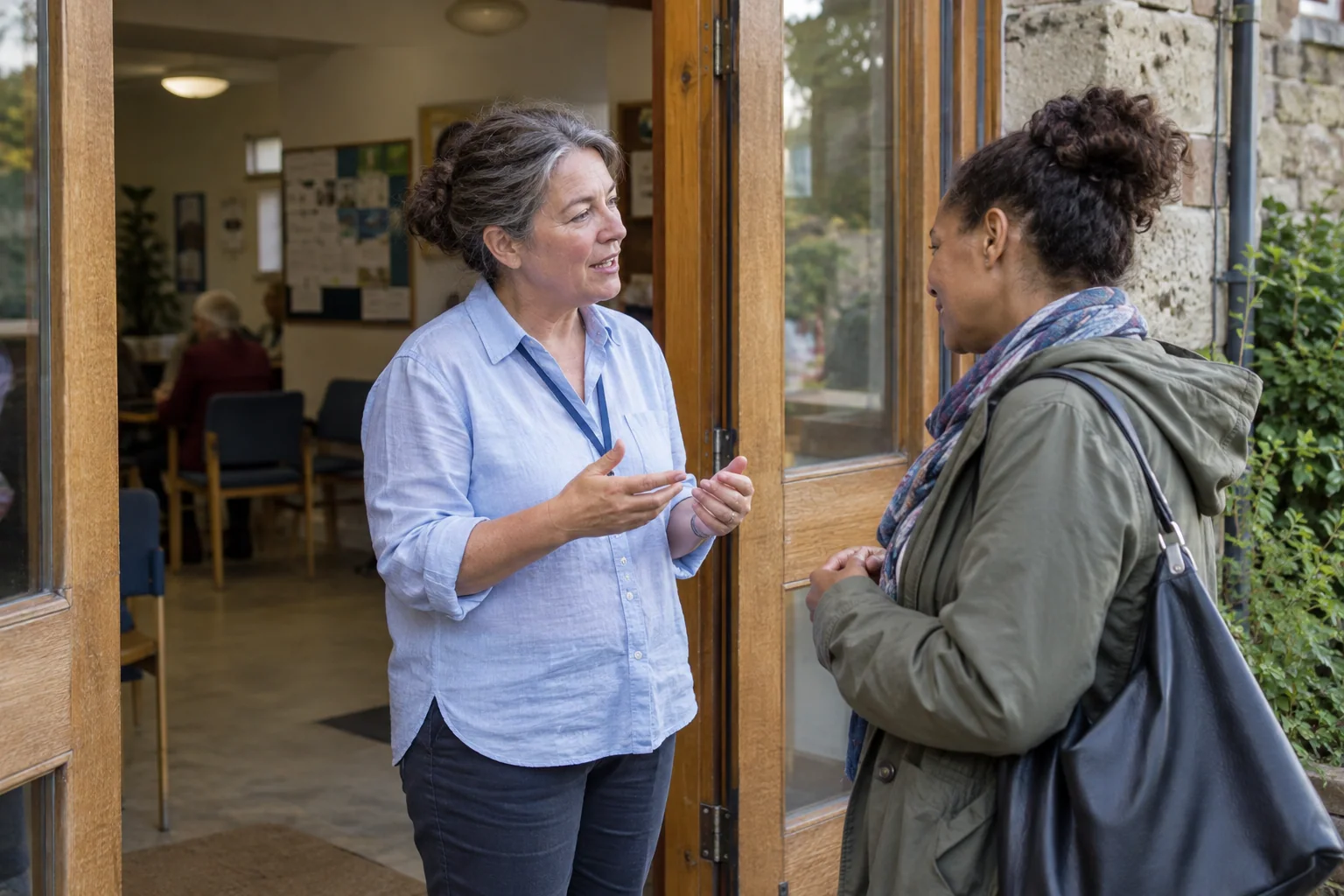A community volunteer talking with a visitor at the center entrance.